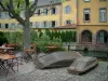 Colmar - La Petite Venise : quai avec deux barques retournées, chaises et tables d'une terrasse de café, arbres, rivière (la Lauch) et maison à la façade jaune en arrière-plan