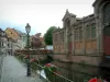 Colmar - La Petite Venise : quai de la Poissonnerie orné de fleurs, maisons colorées à colombages, halles, petit pont fleuri et rivière (la Lauch)