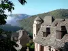 Conques - Tour du château d'Humières et maisons aux toits de lauzes du village médiéval, avec vue sur le paysage verdoyant alentour