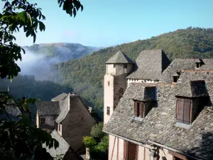 Conques - Tour du château d'Humières et maisons aux toits de lauzes du village médiéval, avec vue sur le paysage verdoyant alentour