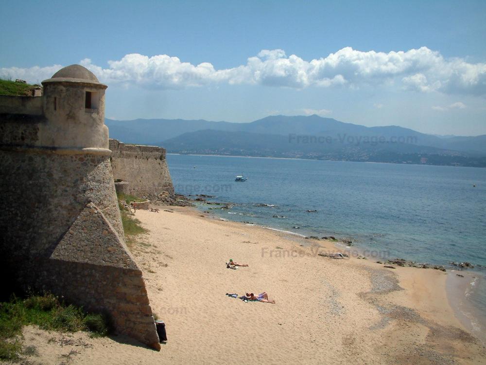 Guide de Corse - Ajaccio - Citadelle avec plage de sable, mer méditerranée, nuages et collines en arrière-plan