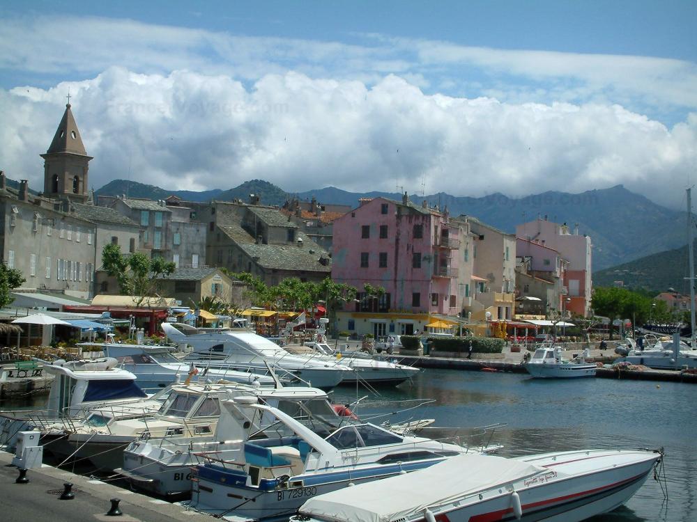 Guide de Corse - Saint-Florent - Port de plaisance avec des bateaux, clocher de l'église et maisons de la station balnéaire
