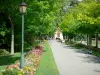 Coulommiers - Parc des Capucins : allée bordée de bancs, de fleurs et d'arbres, lampadaire en premier plan