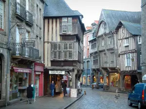 Dinan - Rue pavée bordée d'anciennes demeures à porches et à pans de bois, et de petits commerces