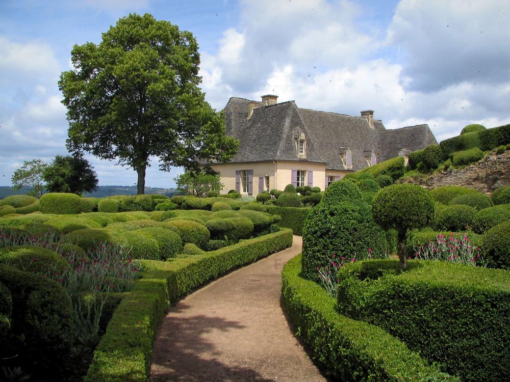 Guide de la Dordogne - Jardins de Marqueyssac - Allée et buis taillés, arbre, château et nuages dans le ciel, dans la vallée de la Dordogne, en Périgord