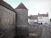 Dourdan - La torre y el foso del castillo, y las fachadas de las casas en la ciudad medieval en el fondo