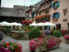 Eguisheim - Bloemen klein pleintje met fontein, terras en koffie huis versierd met geraniums (bloemen)