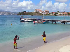 Ensenada Mitan - Playa de arena, muelle, mar y edificios de la Pointe du Bout