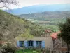 Eus - Maisons aux volets bleus du village avec vue sur le paysage verdoyant alentour