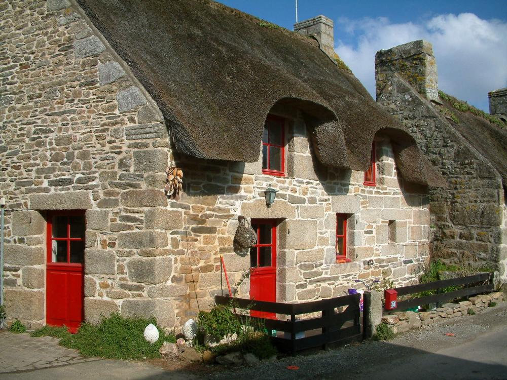 Guide du Finistère - Chaumières - Maison en pierre au toit de chaume avec portes et volets rouges, à Kercanic