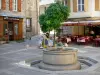 Florac - Platz Louis Dides: Brunnen, Restaurant-Terrasse, Kunstgalerie und Häuserfassaden der Kleinstadt