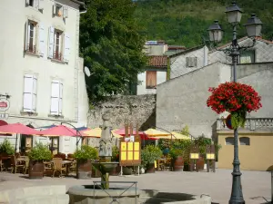 Foix - Platz Pyrène: Brunnen, Strassenlaterne mit Blumen, Terrasse eines Restaurants und Häuserfassaden der Stadt