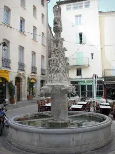 Forcalquier - Saint-Michel fontana decorata con scene gotiche scolpite, terrazza bar e facciate di case nel centro storico
