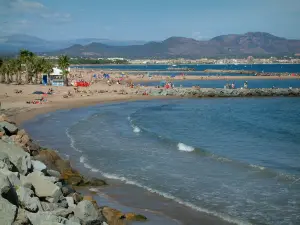 Fréjus - Fréjus-Plage : rochers, mer méditerranée, plages de sable, palmiers et golfe de Fréjus et collines en arrière-plan