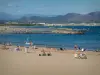 Fréjus - Fréjus-Plage: praia de areia com visitantes de verão, mar Mediterrâneo, rochas, golfo de Frejus e colinas ao fundo