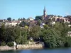 Fumel - Lot rivier, bomen langs het water, woningen in de stad, en de toren van de kerk van St. Anthony domineren alle