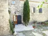 La Garde-Adhémar - Facade and entrance door of a stone house adorned with a cypress tree