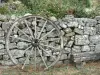 La Garde-Guérin - Vieille roue en bois posée contre un muret de pierres