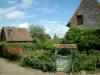 Gerberoy - White wicket with a flower garden, houses of the village and clouds in the blue sky