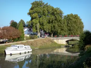 Greenway of the Garonne canal - Garonne canal, moored boats, flower-bedecked bridge and trees; in Buzet-sur-Baïse