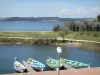 Gruissan - Barcos atracados em primeiro plano com vista para o fim da lagoa, a lagoa Gruissan e a paisagem verde ao redor; no Parque Natural Regional de Narbonnaise, no Mediterrâneo