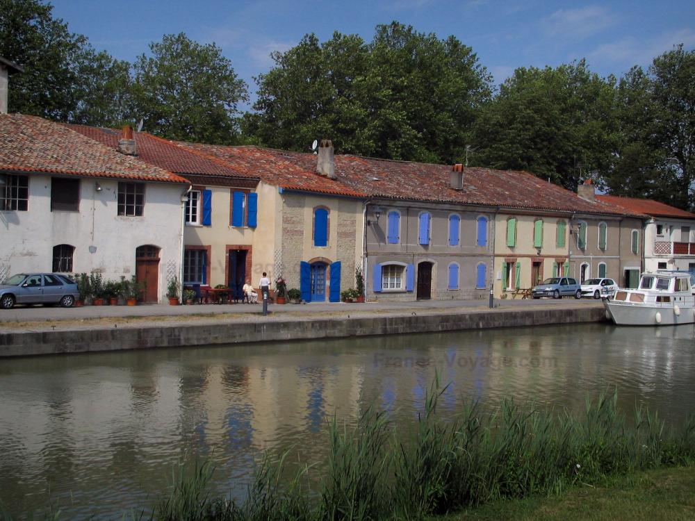 Guide de la Haute-Garonne - Canal du Midi - Maisons aux volets colorés, berges, canal avec un bateau et arbres