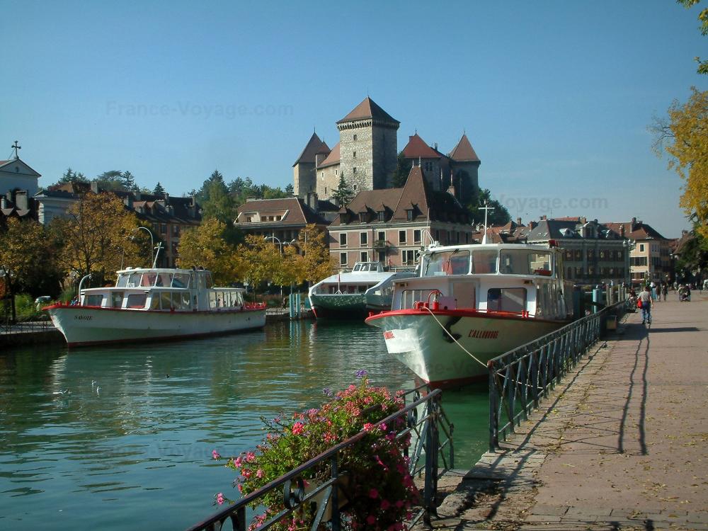 Guide de la Haute-Savoie - Annecy - Canal du Thiou avec son embarcadère (port) et ses bateaux (vedettes), quai Napoléon III (berge), rambarde décorée de fleurs, musée-château et maisons de la vieille ville