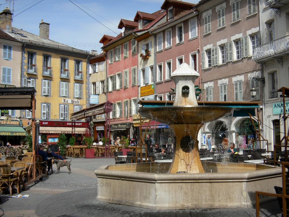 Guide des Hautes-Alpes - Gap - Place Jean Marcellin : fontaine, terrasses de cafés, commerces et maisons aux façades colorées de la vieille ville