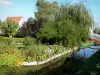 Hortillonnages d'Amiens - Jardin fleuri orné d'arbres et de fleurs au bord de l'eau et petite passerelle enjambant le canal