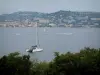 Îles de Lérins - Île Sainte-Marguerite : arbres de l'île en premier plan avec vue sur la mer, les bateaux et le littoral de la Côte d'Azur