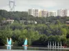 Isla de ocio de Cergy-Pontoise - Actividades náuticas en uno de los estanques (cuerpo de agua) del dominio, árboles al borde del agua y casas y edificios al fondo