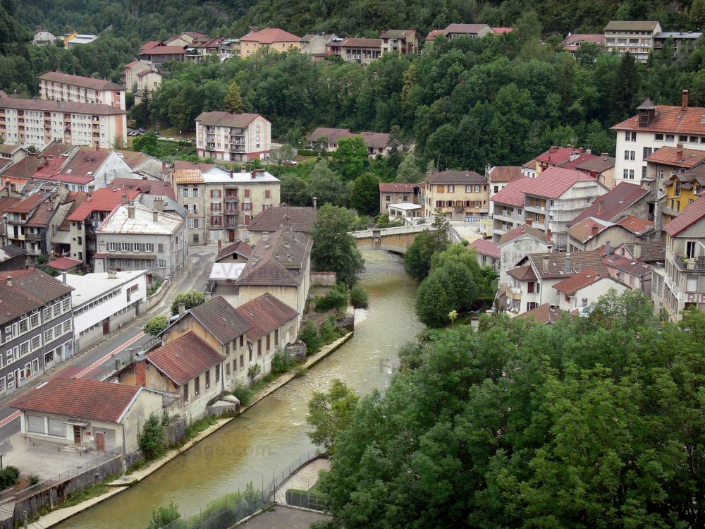 Guide du Jura - Saint-Claude - Maisons, immeubles et arbres au bord de l'eau, pont enjambant la rivière ; dans le Parc Naturel Régional du Haut-Jura