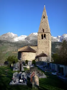 Kirche Mère-Église von Saint-Disdier - Kirche Mère-Église oder Kapelle der Gicons im romanischen Baustil mit Glockenturm aus Stein, und Dach mit Stroh und Schiefer, und Berge des Dévoluy mit schneebedeckten Gipfeln