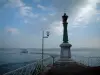 Lac Léman - Rive d'Évian-les-Bains, phare, lampadaire, lac avec un bateau, rive suisse et nuages dans le ciel