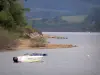 Lac de Pareloup - Plateau du Lévézou : lac de Pareloup et ses rives verdoyantes, bateau flottant sur l'eau en premier plan