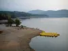 Lac de Saint-Cassien - Plage, arbres, pédalos de couleur jaune amarrés à un ponton, plan d'eau, rives et collines couvertes de forêts