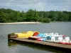 Lac de Sillé - Sillé Plage, sur la commune de Sillé-le-Guillaume, dans le Parc Naturel Régional Normandie-Maine : pédalos amarrés, plan d'eau et arbres de la forêt de Sillé