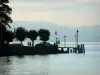 Lake Geneva - Lago, margem de Meillerie com árvores, bandeiras e postes de luz na sombra, montanhas ao fundo