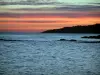 Landscapes of the French Riviera coast - Red sky with grey clouds at the sunrise, coast, cliffs (reefs) and the Mediterranean Sea