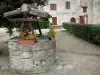 Larressingle - Puits fleuri, et maison en pierre abritant l'office de tourisme en arrière-plan