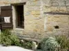 Larressingle - Façade d'une maison en pierre, banc et plantes
