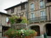 Lisle-sur-Tarn - Praça de arcada (lugar coberto) com uma imprensa decorada com flores e casas de tijolo do bastide