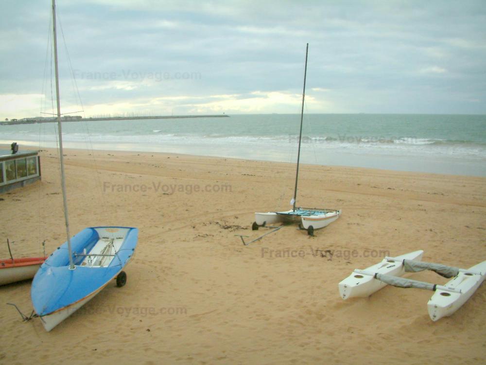 Guide de la Loire-Atlantique - Paysages du littoral de Loire-Atlantique - Plage de sable avec des bateaux, mer (océan Atlantique) et ciel orageux