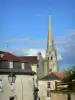 Loudun - Campanile della chiesa Saint-Pierre-du-Mart sormontato da una guglia, case della città, nuvole nel cielo blu