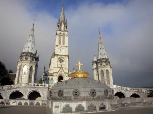 Lourdes - Domaine de la Grotte (heiligdommen, religieuze stad): koepel van de Basiliek van Onze Lieve Vrouw van de Rozenkrans met een kroon en een gouden kruis, torentjes en de klokkentoren van de Basiliek van de Onbevlekte Ontvangenis (Bovenkerk) neogotische