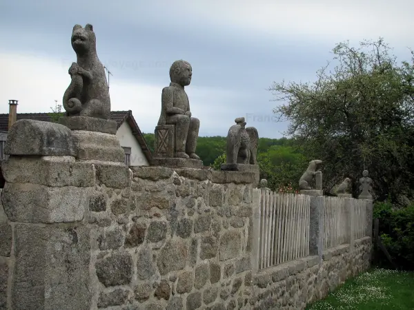 Masgot - Mauer aus Stein, die von  einer Skulptur überwunden ist