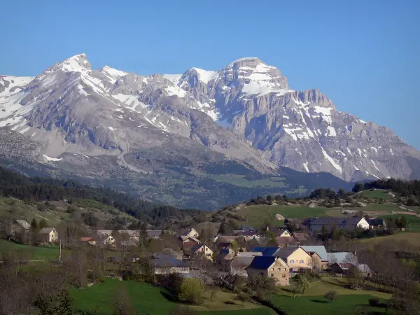 Massif du Dévoluy - Maisons d'un village, prairies, arbres et montagnes aux cimes enneigées (neige)