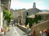 Ménerbes - Rue du village avec des maisons et une exposition de tableaux