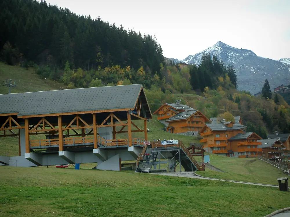 Méribel - Remontée mécanique et résidences-chalets de la station de ski (sports d'hiver), arbres en automne, forêt de sapins et montagne au sommet recouvert de neige