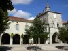 Monflanquin - Medieval bastide town: Place des Arcades square with trees, facade of the Bastides museum, home of the Prince Noir (Black Prince) with its gemel windows, and bell tower of the Saint-André church overlooking the place